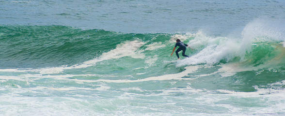 surfer surfs face of large powerful wave on the ocean 