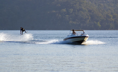 waterskier jumps into air behind fast speedboat 