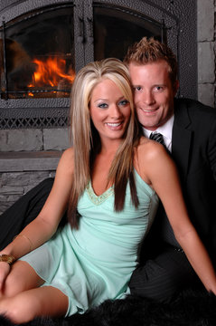 beautiful couple sitting in front of fireplace smiling