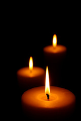 Three burning candles (focus on front candle)