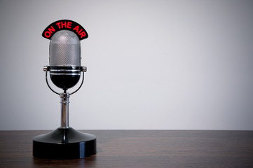 Retro microphone with an 'On the Air' illuminated sign on a desk