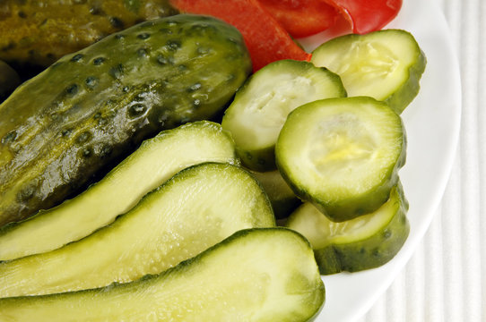 Pickled cucumbers arranged on a white dish.