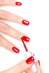 Manicurist applying red nail polish on female fingers.