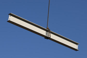 Steel girder swinging from a crane on a construction site