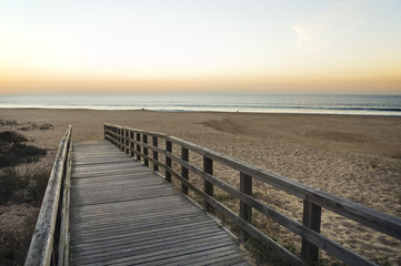Fototapeta na wymiar Drewniana kładka prowadzi do pustej plaży