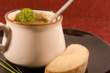 Mug of Soup on Black Plate with Bread and Garnish