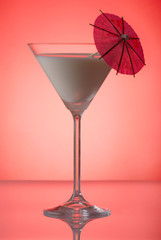Milky cocktail with umbrella on red background