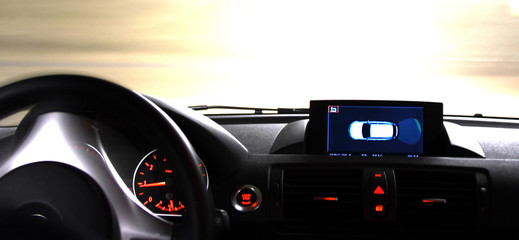 Dashboard part of the car with GPS and driving wheel on the road