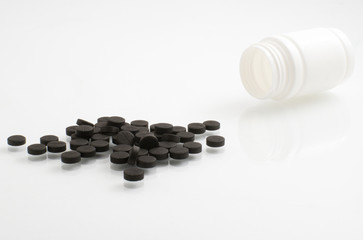 black pills isolated and white bottle