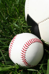 Baseball and soccerball sitting on a field