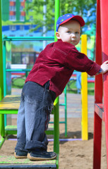 Obraz premium 3-year-old boy on swings on the children's playground