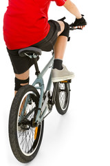 Young boy in red T-shirt cycling on BMX . Rear view.