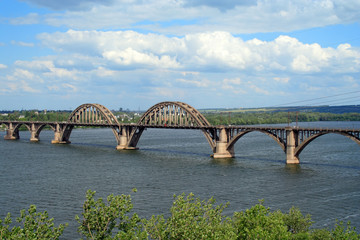 concrete railroad bridge with arches on a river 