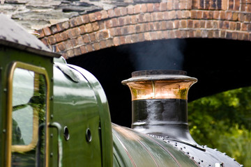 Detail of a steam railway engine about to pass under a bridge