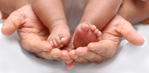 close up of a father's hand cradling babies feet - obrazy, fototapety, plakaty
