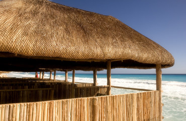 Straw and bamboo cabanas on the beach in front of a resort