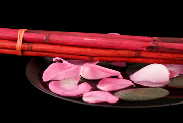Rosenblüten mit Bambus auf schwarzem Teller