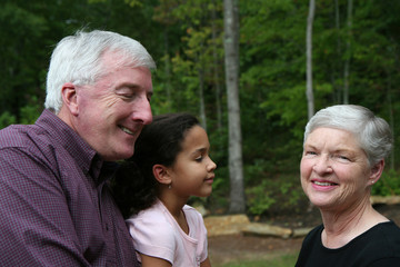 Happy Senior Couple smiling outside with grandchild
