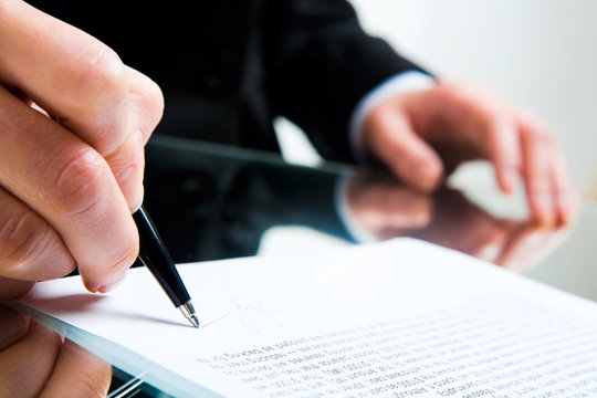 Closeup of business lady’s hand with pen signing a contract 