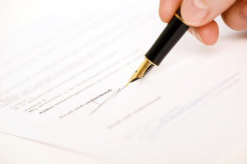 someone signing a document with a pen.  