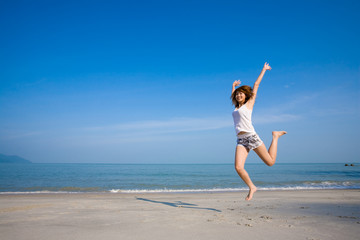 woman jumping happily having fun by the beach