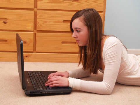 Teenage Girl Typing On A Laptop Computer