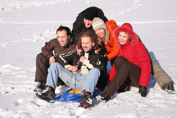 Fototapeta na wymiar five friends with plastic sled sit on snow