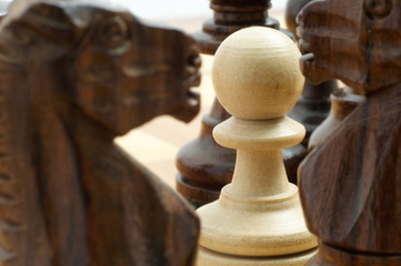 white pawn chessman surrounded by black pieces