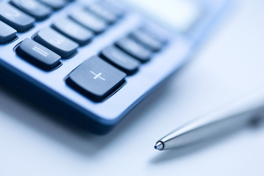 Calculator and pen in blue color, shallow focus