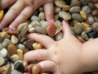 Young Child's Hands in Pebbles