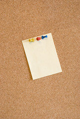 Blank page attached to corkboard with three colorful pins