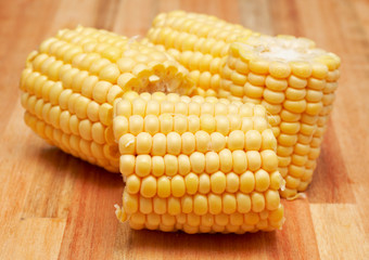 Sweet yellow corn cobs on a wooden chopping board