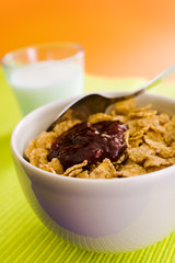 Corn flakes on the vase with jam and spoon