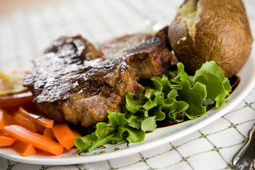 A juicy t-bone steak with baked potato and vegetables
