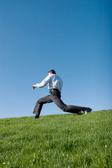 Businessman doing karate moves on green grass
