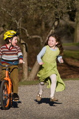 Fototapeta premium boy on bike, girl running beside him