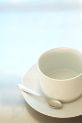 Empty white ceramic coffee cup and silver teaspoon 