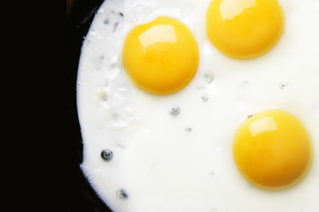 Three fried eggs close-up with space for text on left