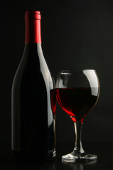 Wine bottle and footed glass over black background