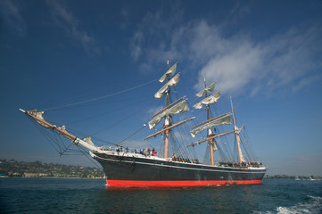 Fototapeta na wymiar Tall Ship under sail with the shore in the background