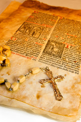 Rosary with cross over the old parchment text. 