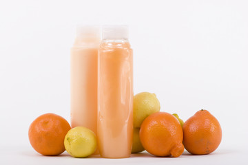 Shampoo and conditioner in bottles with few lemons and oranges.