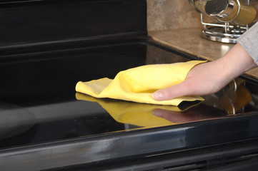 Woman's hand with a cloth cleaning ceramic cooktop