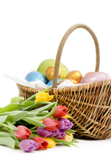 Basket of chocolate easter eggs with a bunch of fresh tulips