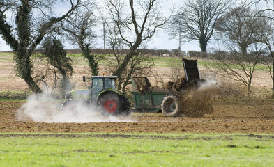 Tractor muck spreading during late winter, steam from the manure