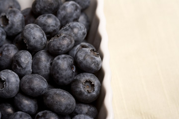 a white cup full of fresh ripe blueberries