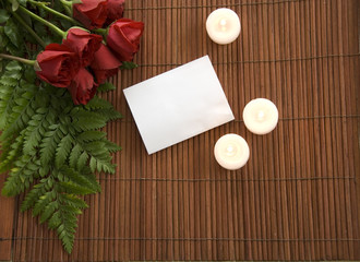 red roses on bamboo with candles and notecard