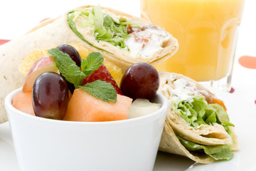 Healthy lunch - tortilla wraps, fruit salad and orange juice