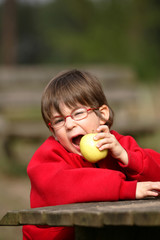 garçon avec des lunettes entrain de manger une pomme