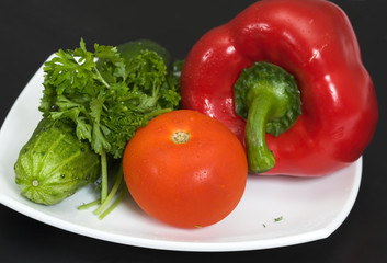 Fototapeta na wymiar Fresh vegetables on a white plate and a black background